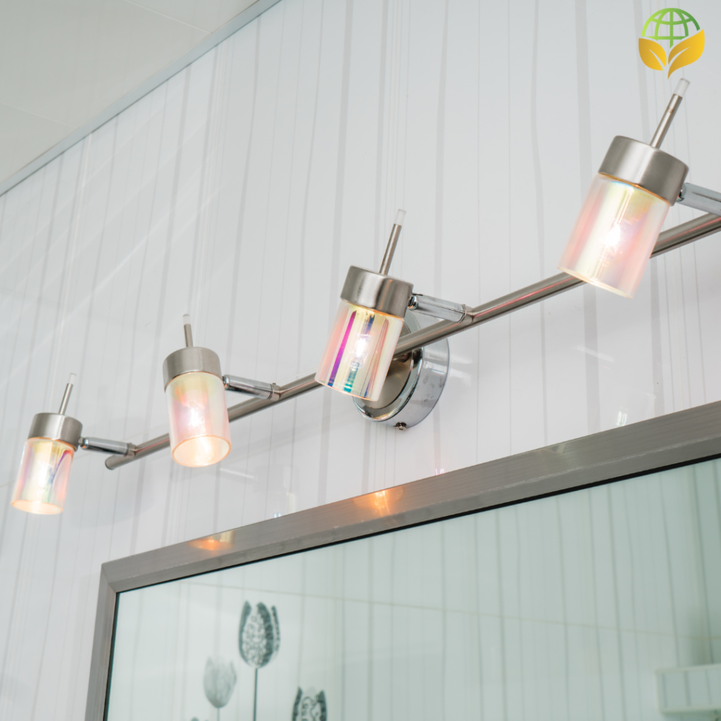 Three modern wall-mounted light fixtures along a metal track on a white wall. The fixtures have a metallic finish with partially frosted glass that diffuses the light. The reflection and colors suggest they are turned on, casting a warm glow on the surroundings.