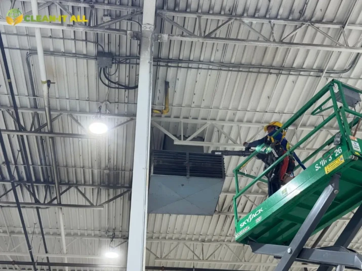 Certified cleaner using a boom lift to clean high ceilings and rafters on a Calgary film set